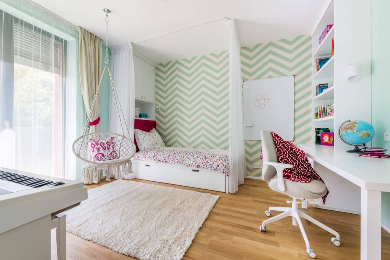 Bílý koberec s&nbsp;dlouhým vlasem v&nbsp;dívčím pokoji, pracovní židle na&nbsp;kolečkách stojí vedle něj na&nbsp;dřevěné podlaze